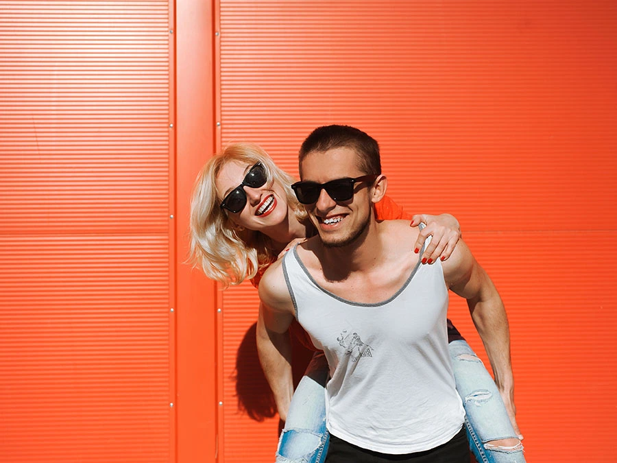 couple-smiling-piggyback-sunglasses